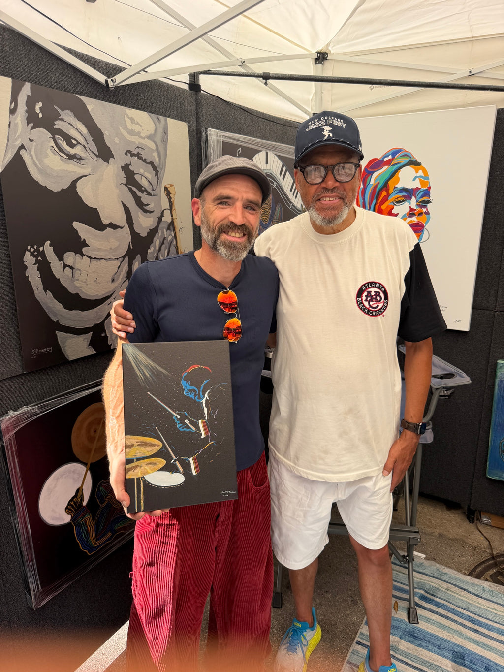 A collector holding the Blue Drummer 10x15 Studio Edition canvas at an O'Bannon Studios art fair booth